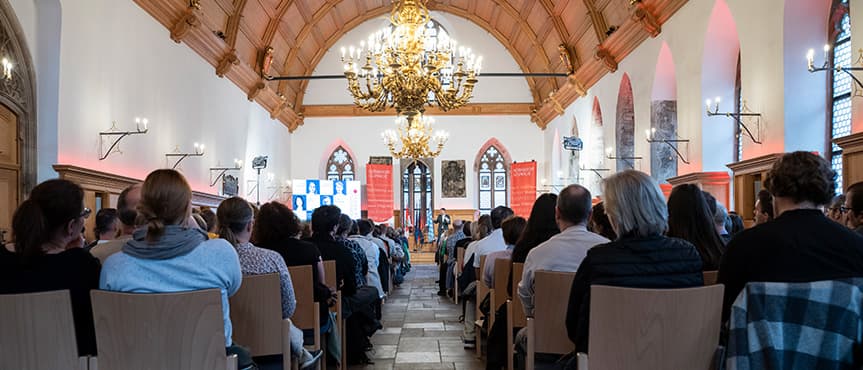 Blick von hinten auf das Publikum der Nürnberger Gespräche 2026 im Historischen Rathaussaal in Nürnberg.