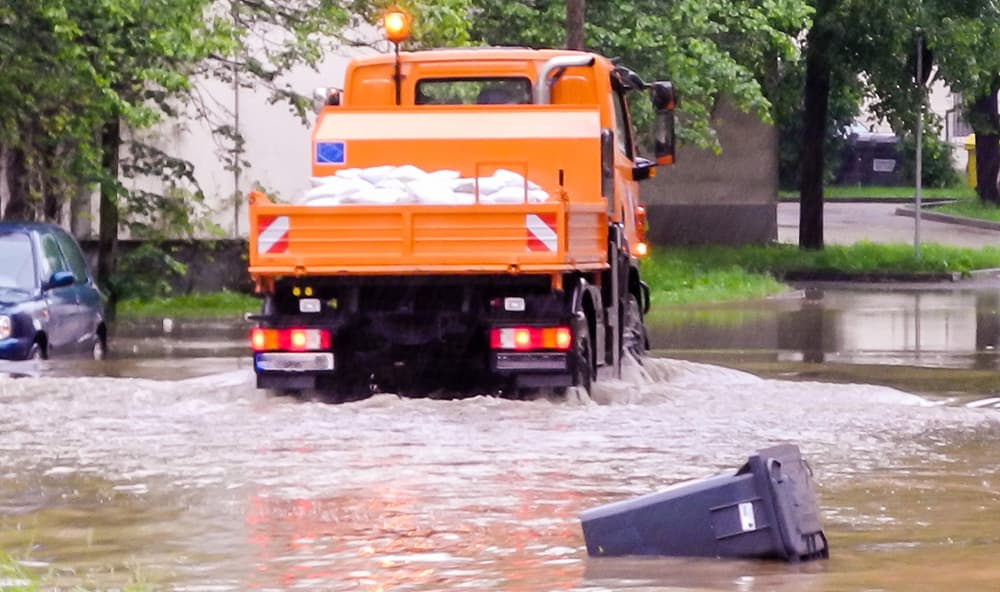 Ein Müllauto fährt bei Hochwasser in einer überschwemmten Straße.