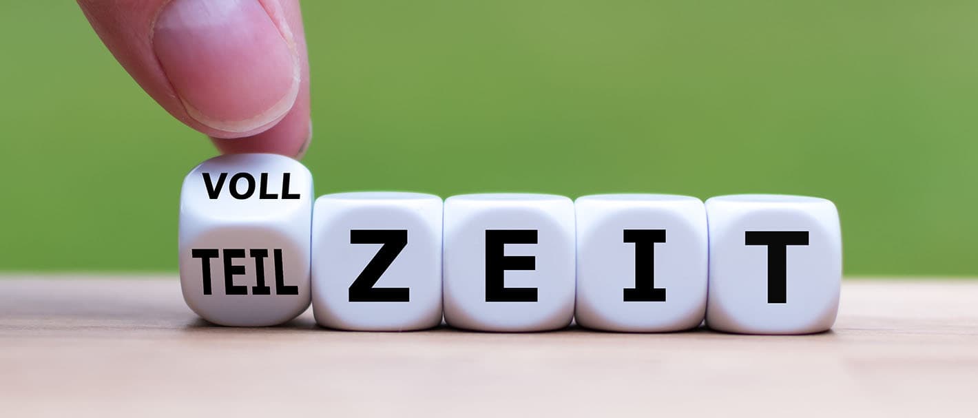 Eine Hand dreht den ersten Würfel einer Würfelreihe mit Buchstaben und ändert so das Wort "Vollzeit" in "Teilzeit" oder umgekehrt.