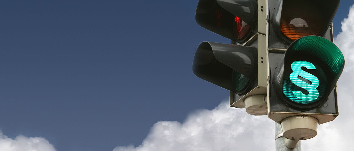 Auf einer Ampel leuchtet ein grünes Paragraphenzeichen.