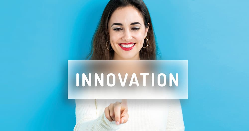 Lächelnde Frau drückt einen Button mit der Aufschrift Innovation, der vor ihr im Raum schwebt. Das Bild ist das Kennungsbild des Dossiers "Mach es einfach".