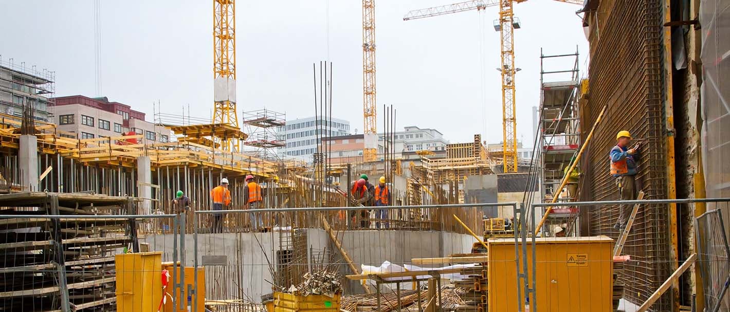 Großbaustelle mit Arbeitern vor städtischer Kulisse