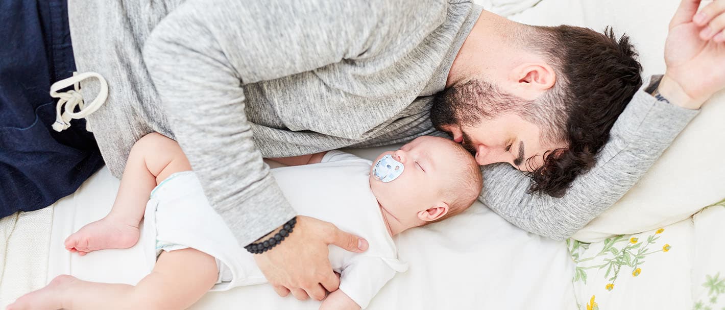 Vater kuschelt sich an sein schlafendes Baby