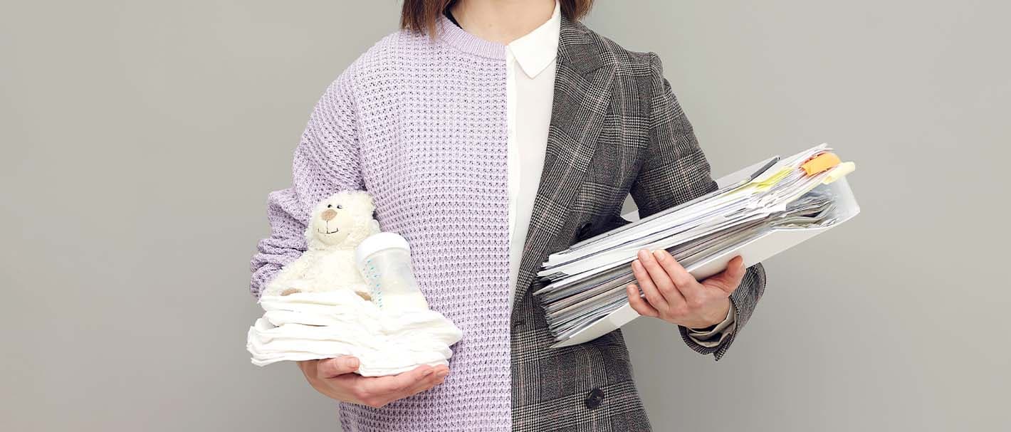 Eine Frau, die halb mit einem grauen Jackett, halb mit einem zartrosa Pullover bekleidet ist, hält in der einen Hand einen Aktenordner, in der anderen Baby-Utensilien.